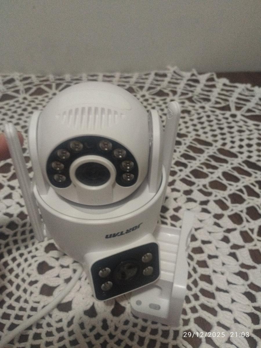 Câmera de vigilância branca com design compacto vista de cima sobre superfície rendada