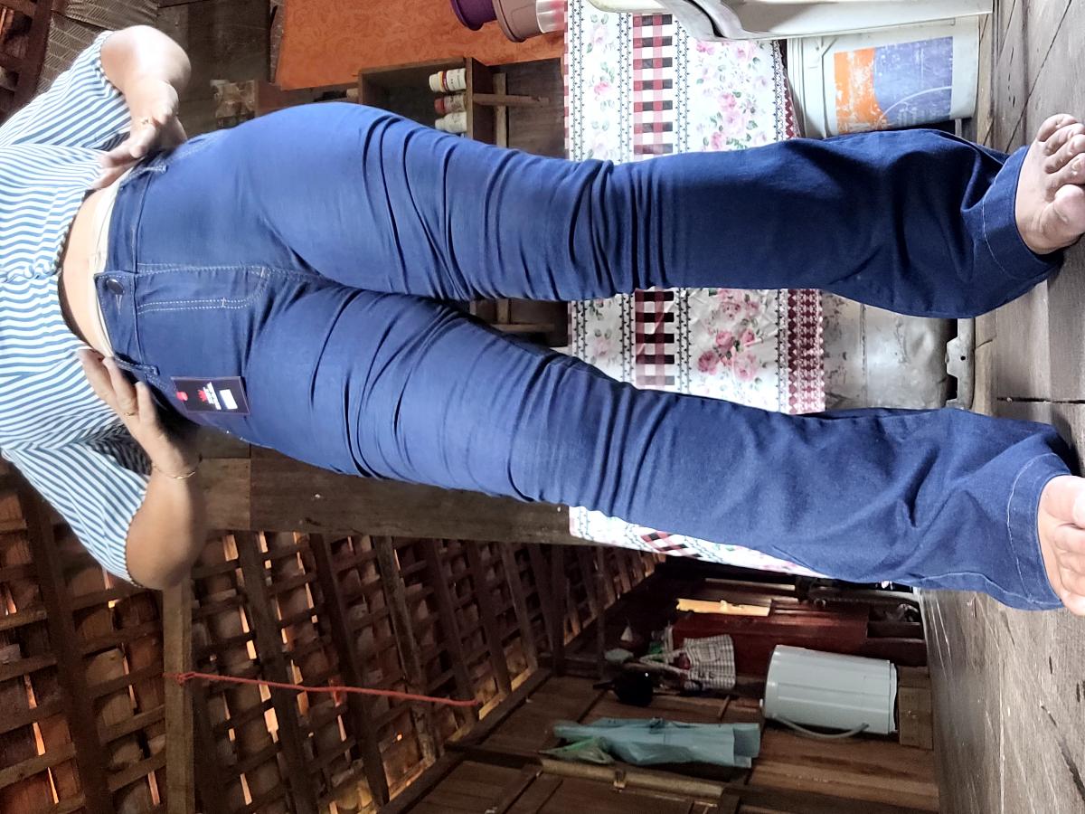 Vista lateral da calça jeans flare com etiqueta de preço em ambiente rústico