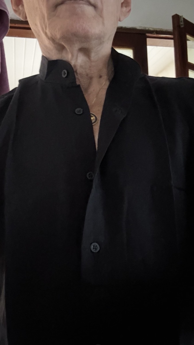 Close no colarinho estilo padre de camisa social preta com botões visíveis