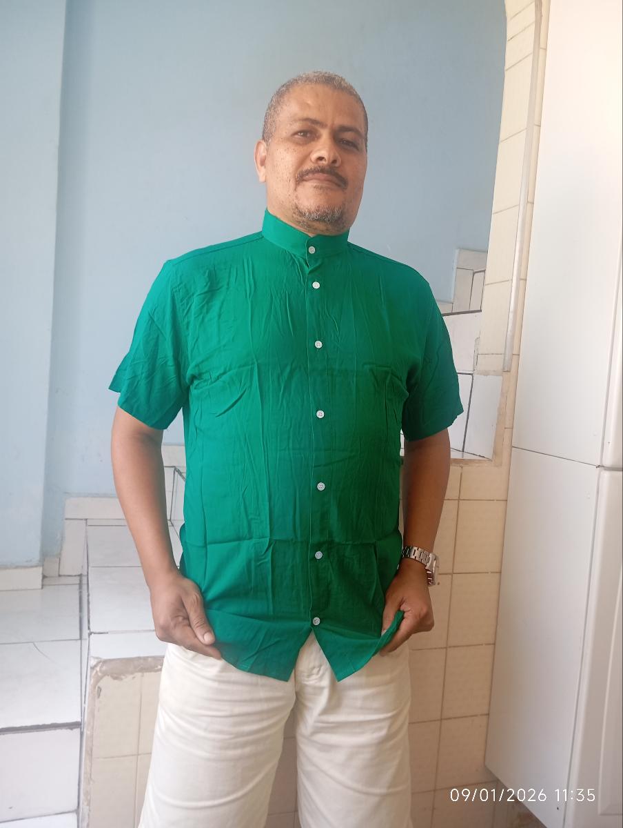 Homem vestindo camisa gola padre manga curta na cor verde com calça clara